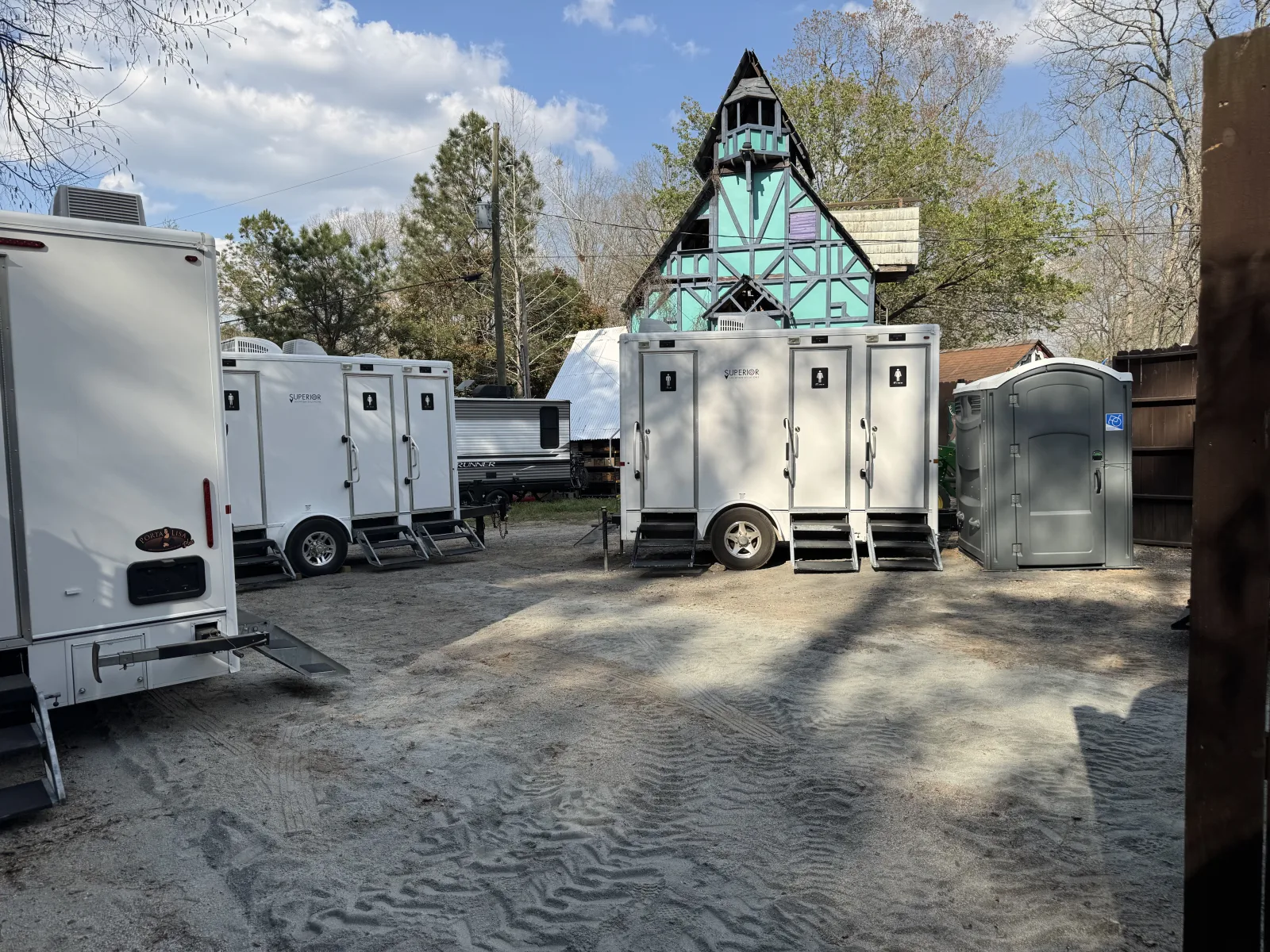 Superior Location Solutions restroom trailers set beside a timber-framed village building at the Georgia Renaissance Festival in Fairburn